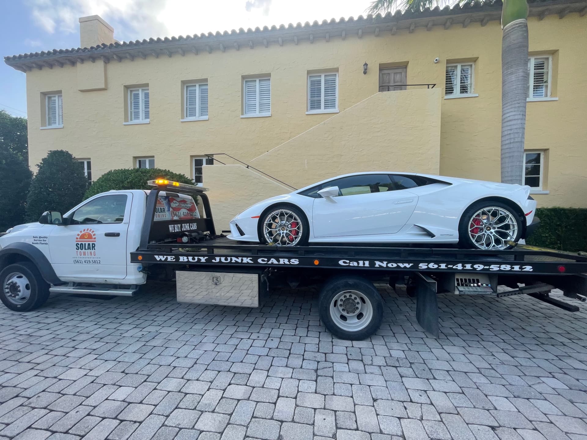 High Solar Towing flatbed transporting a white Lamborghini in Delray Beach