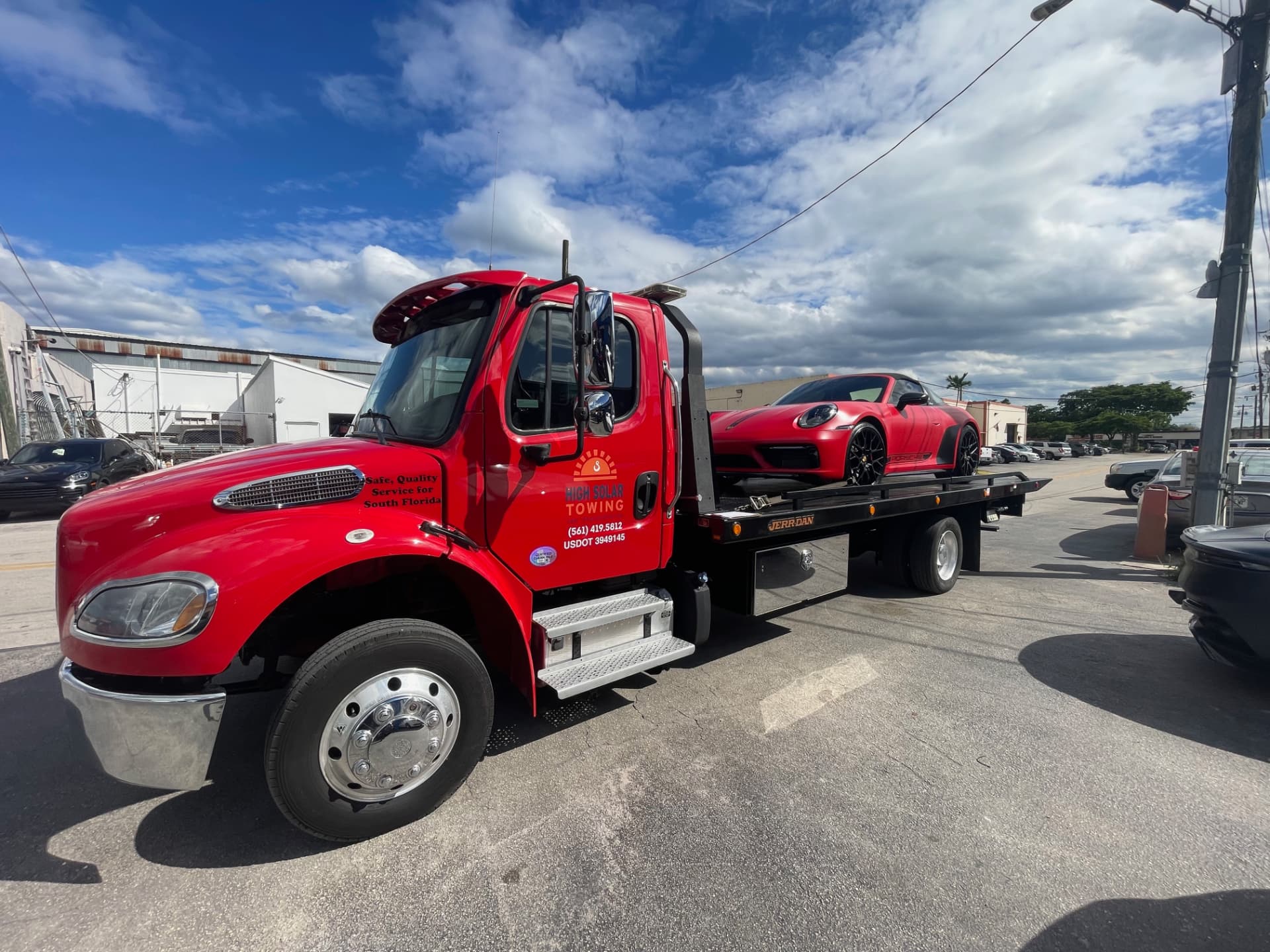High Solar Towing red flatbed truck transporting a Porsche in South Florida